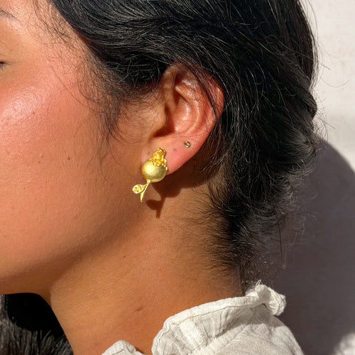 Close-up of a person wearing a gold earring with a white background