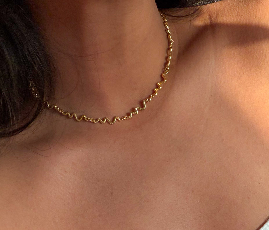 Close-up of a person wearing a gold chain necklace.