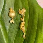 Gold frog earrings on a green leaf 