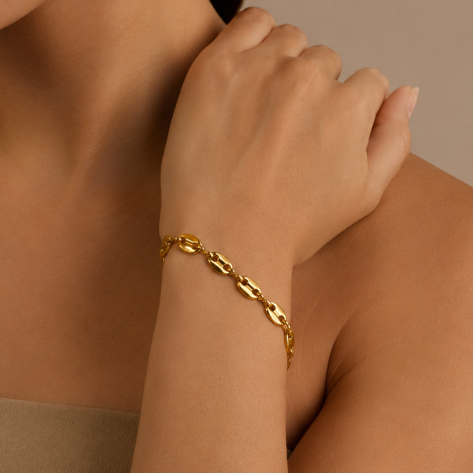 Gold chain bracelet on a person's wrist against a neutral background