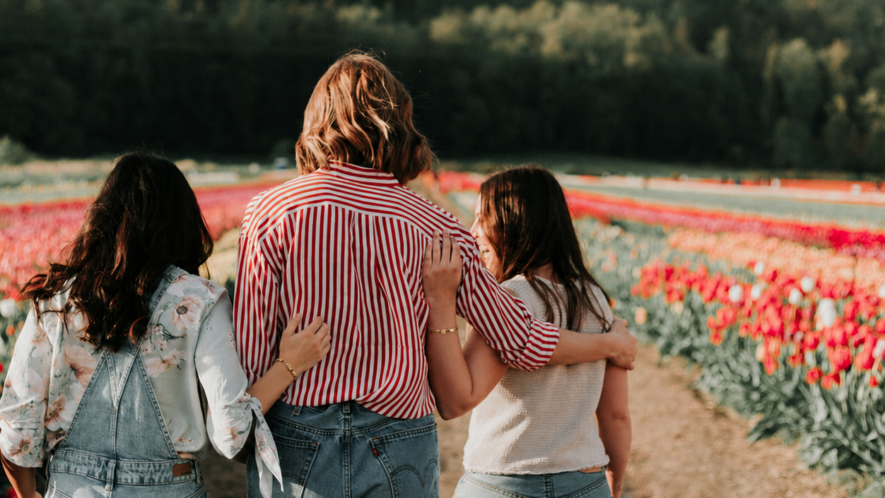 Three people standing in a tulip field with a scenic background