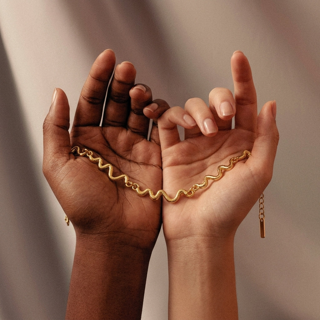 Two hands holding a gold chain against a neutral background