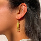 Close-up of a person wearing a gold earring with a fish design.