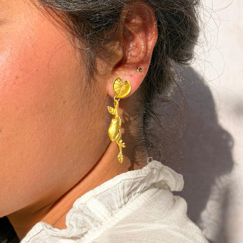Close-up of a person wearing gold heart-shaped earrings with a blurred background